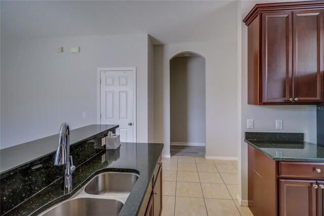 kitchen with dark stone counters, light tile patterned flooring, and sink