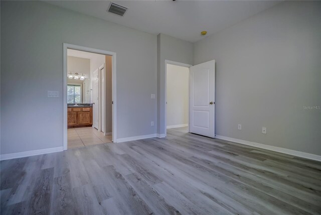 unfurnished bedroom featuring connected bathroom and light hardwood / wood-style floors