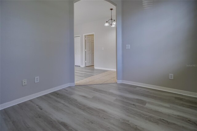 unfurnished room with a notable chandelier and light hardwood / wood-style floors