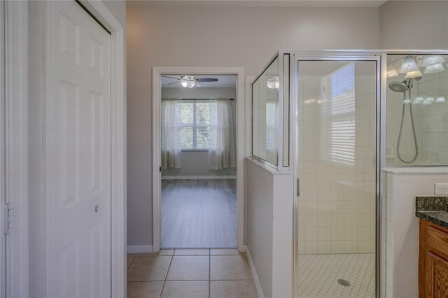 bathroom with ceiling fan, vanity, a shower with shower door, and tile patterned floors