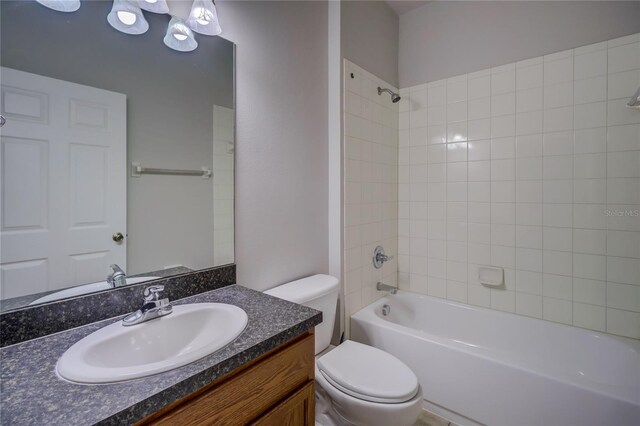 full bathroom featuring vanity, tiled shower / bath combo, and toilet