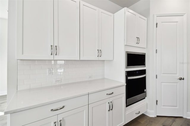 kitchen with white cabinetry, tasteful backsplash, light stone counters, dark hardwood / wood-style floors, and oven