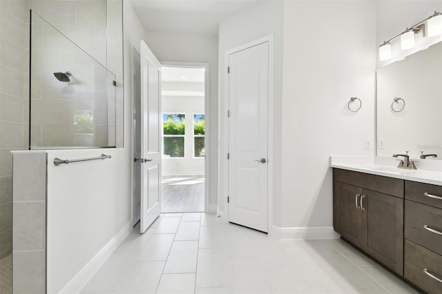 bathroom with tile patterned flooring, vanity, and tiled shower