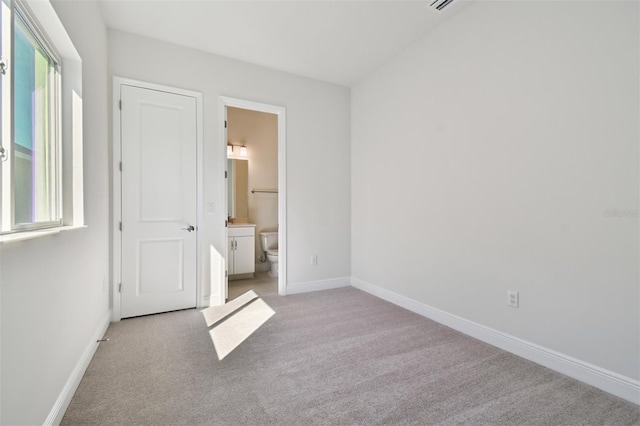 unfurnished bedroom with light colored carpet and ensuite bath