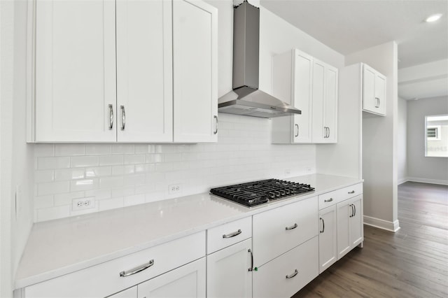 kitchen featuring dark hardwood / wood-style floors, stainless steel gas stovetop, white cabinetry, backsplash, and wall chimney exhaust hood