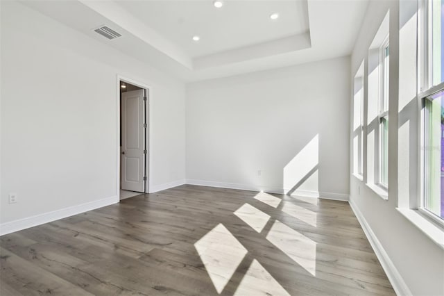 empty room featuring dark hardwood / wood-style floors and a tray ceiling