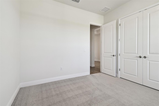 unfurnished bedroom featuring light carpet and a closet