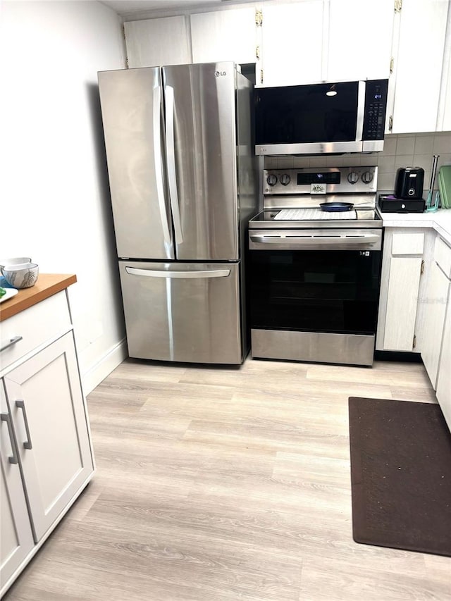 kitchen with white cabinets, stainless steel appliances, light hardwood / wood-style flooring, and backsplash