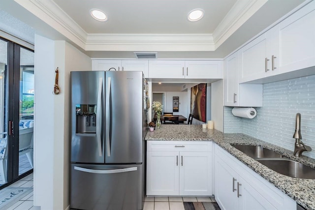 kitchen featuring white cabinets, stainless steel fridge, sink, light stone countertops, and crown molding