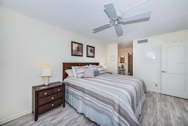 bedroom featuring light hardwood / wood-style flooring, connected bathroom, ceiling fan, and a textured ceiling