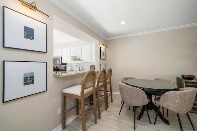 dining area with light hardwood / wood-style flooring and ornamental molding