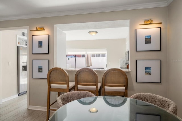 dining area with crown molding and light hardwood / wood-style floors