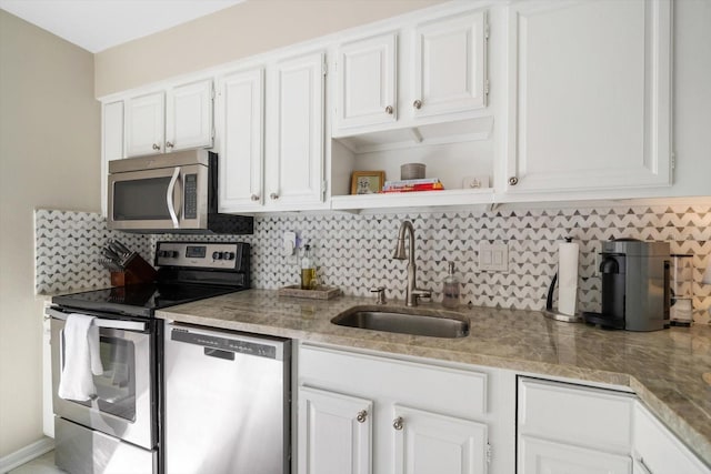 kitchen with backsplash, stainless steel appliances, white cabinets, and sink