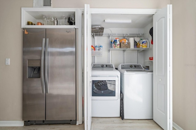 washroom featuring washing machine and clothes dryer and light hardwood / wood-style flooring