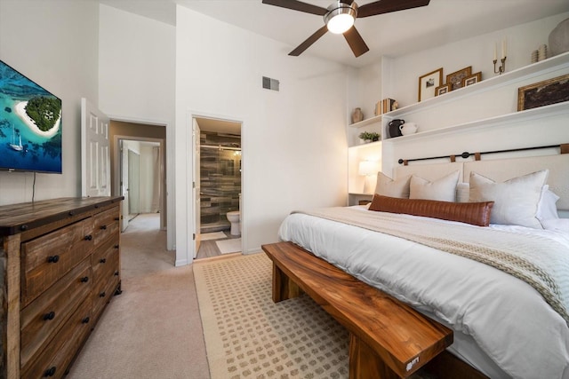 bedroom with connected bathroom, a towering ceiling, ceiling fan, and light colored carpet