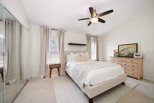 bedroom featuring ceiling fan, light colored carpet, a closet, and vaulted ceiling