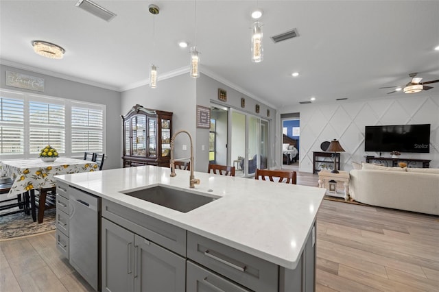 kitchen with an accent wall, a sink, visible vents, gray cabinets, and dishwasher