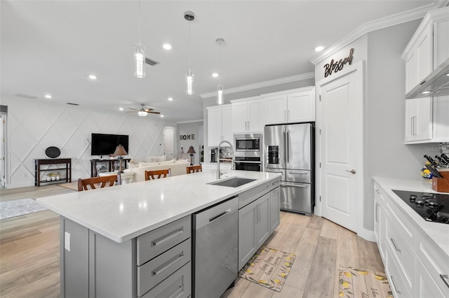 kitchen with appliances with stainless steel finishes, sink, an island with sink, decorative light fixtures, and crown molding