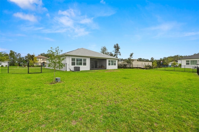 rear view of property with central AC, a yard, and a fenced backyard