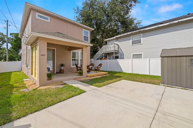 back of house with a yard, a patio area, a fenced backyard, and stucco siding
