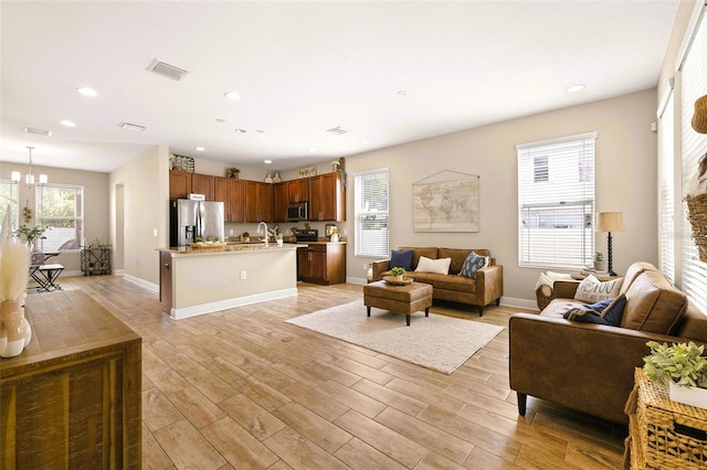 living area with recessed lighting, light wood-type flooring, visible vents, and a notable chandelier