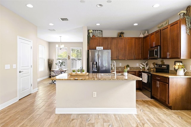 kitchen with light stone counters, visible vents, a sink, appliances with stainless steel finishes, and a notable chandelier
