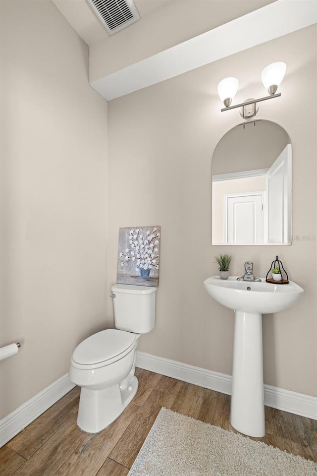 bathroom featuring wood finished floors, visible vents, toilet, and baseboards