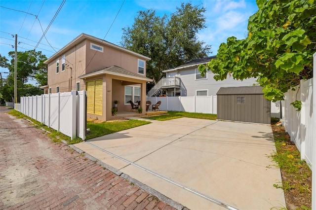 rear view of property featuring a storage shed, a fenced backyard, a patio area, an outdoor structure, and stucco siding