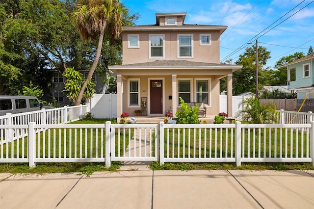 traditional style home featuring stucco siding, a fenced front yard, a front yard, and covered porch