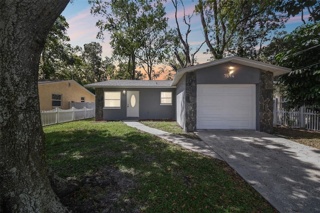 ranch-style house featuring a garage and a lawn