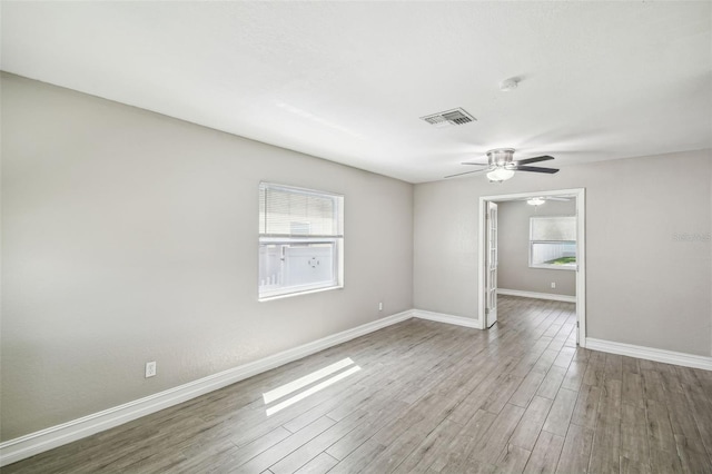 spare room featuring ceiling fan, a healthy amount of sunlight, and wood-type flooring