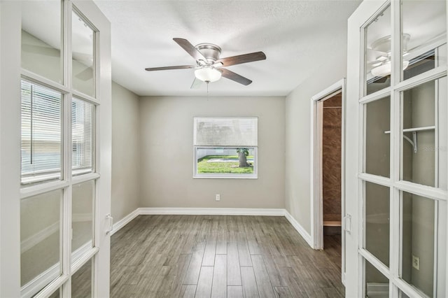 spare room with a textured ceiling, hardwood / wood-style flooring, a healthy amount of sunlight, and ceiling fan