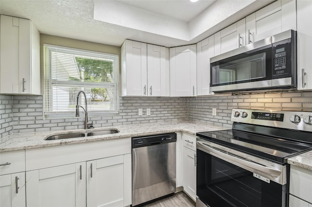 kitchen with decorative backsplash, white cabinetry, stainless steel appliances, and sink