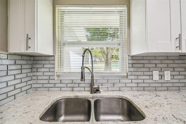 kitchen featuring white cabinetry, light stone countertops, sink, and plenty of natural light