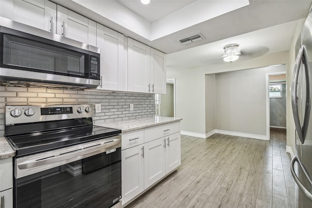 kitchen featuring white cabinetry, light hardwood / wood-style floors, stainless steel appliances, and light stone countertops