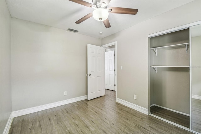 unfurnished bedroom with hardwood / wood-style flooring, a closet, and ceiling fan