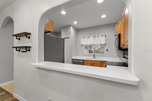 214 Cape Harbour Loop Unit 105, Bradenton, FL 34212 - kitchen featuring appliances with stainless steel finishes, a sink, arched walkways, light countertops, and wood finished floors