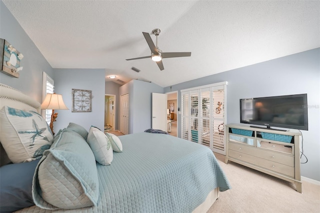 bedroom with a textured ceiling, ceiling fan, light colored carpet, and vaulted ceiling