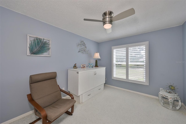 living area with ceiling fan, carpet flooring, and a textured ceiling