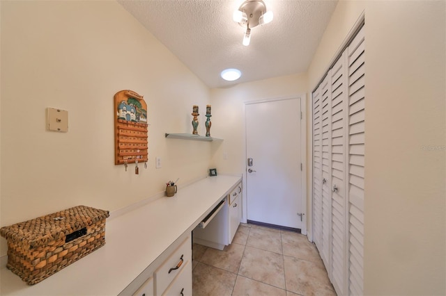 clothes washing area with a textured ceiling and light tile patterned floors