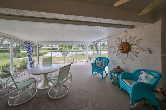 sunroom with beamed ceiling and a water view