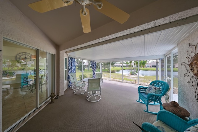 unfurnished sunroom featuring lofted ceiling with beams, ceiling fan, a water view, and a wealth of natural light