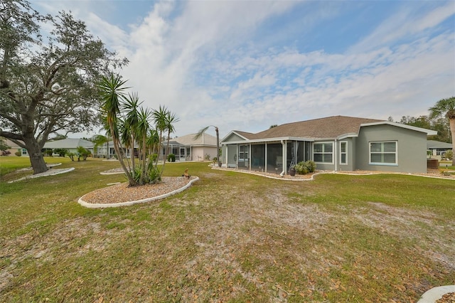 rear view of house with a lawn and a sunroom