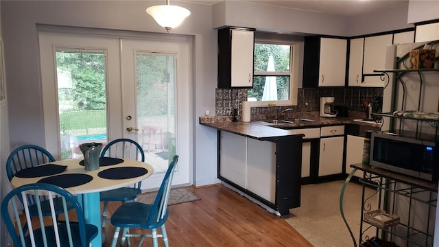 kitchen with decorative backsplash, white cabinetry, light hardwood / wood-style flooring, and plenty of natural light