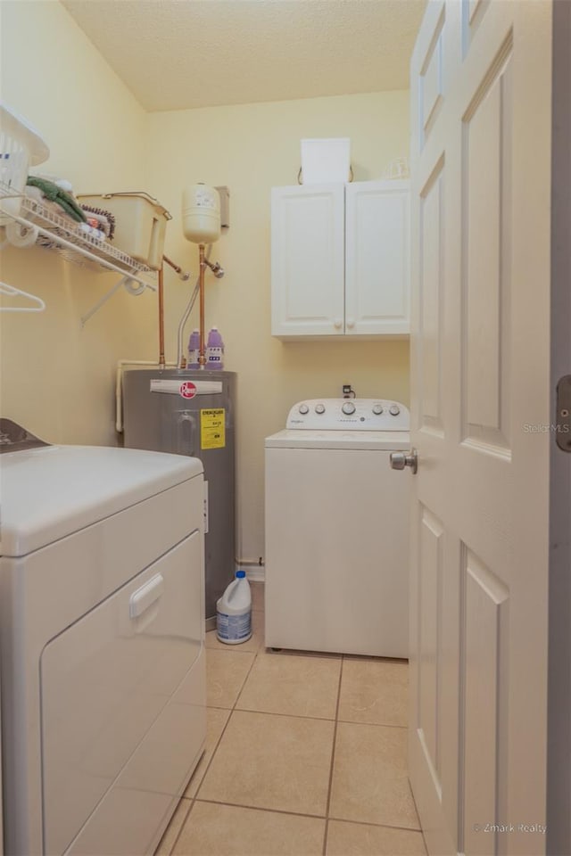 laundry room with cabinets, light tile patterned floors, washing machine and dryer, and water heater