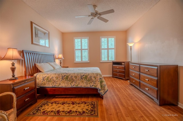 bedroom featuring ceiling fan, light hardwood / wood-style flooring, and a textured ceiling