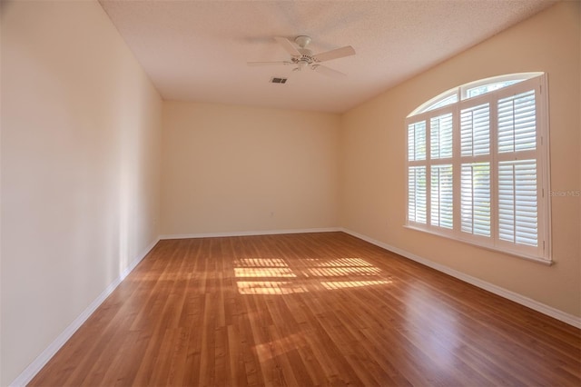 empty room featuring ceiling fan, hardwood / wood-style floors, and a textured ceiling