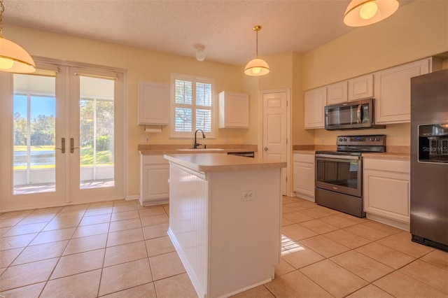 kitchen featuring appliances with stainless steel finishes, light tile patterned floors, white cabinetry, and hanging light fixtures