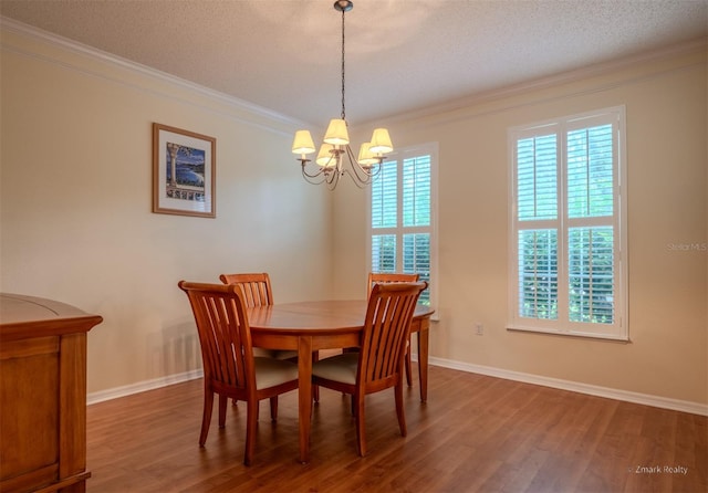 dining area featuring hardwood / wood-style floors, a textured ceiling, ornamental molding, and a notable chandelier