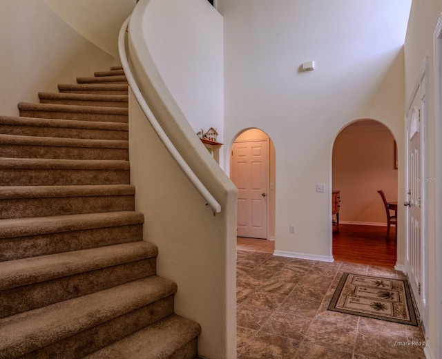 staircase featuring wood-type flooring and a towering ceiling